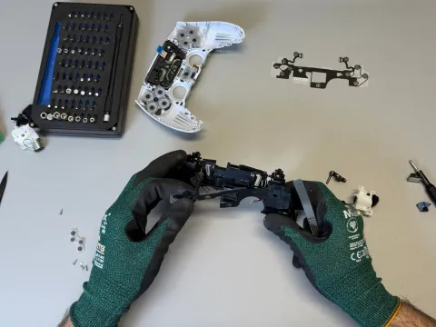 Tehnician desfăcând un controller DualSense ca să ajungă la modulele de stick