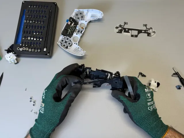 Tehnician desface un controller DualSense PS5 pe bancul de lucru din atelierul Clinica Consolelor